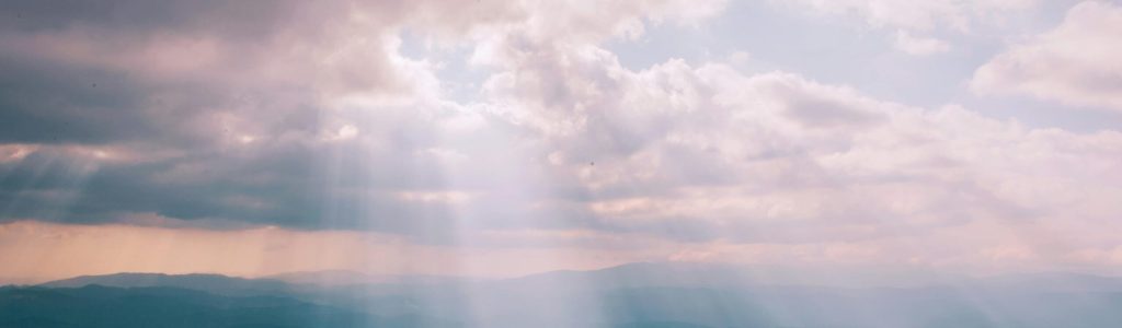 pexels-photo-1403550-1403550 Gentle sunbeams breaking through a cloudy sky over a serene landscape.